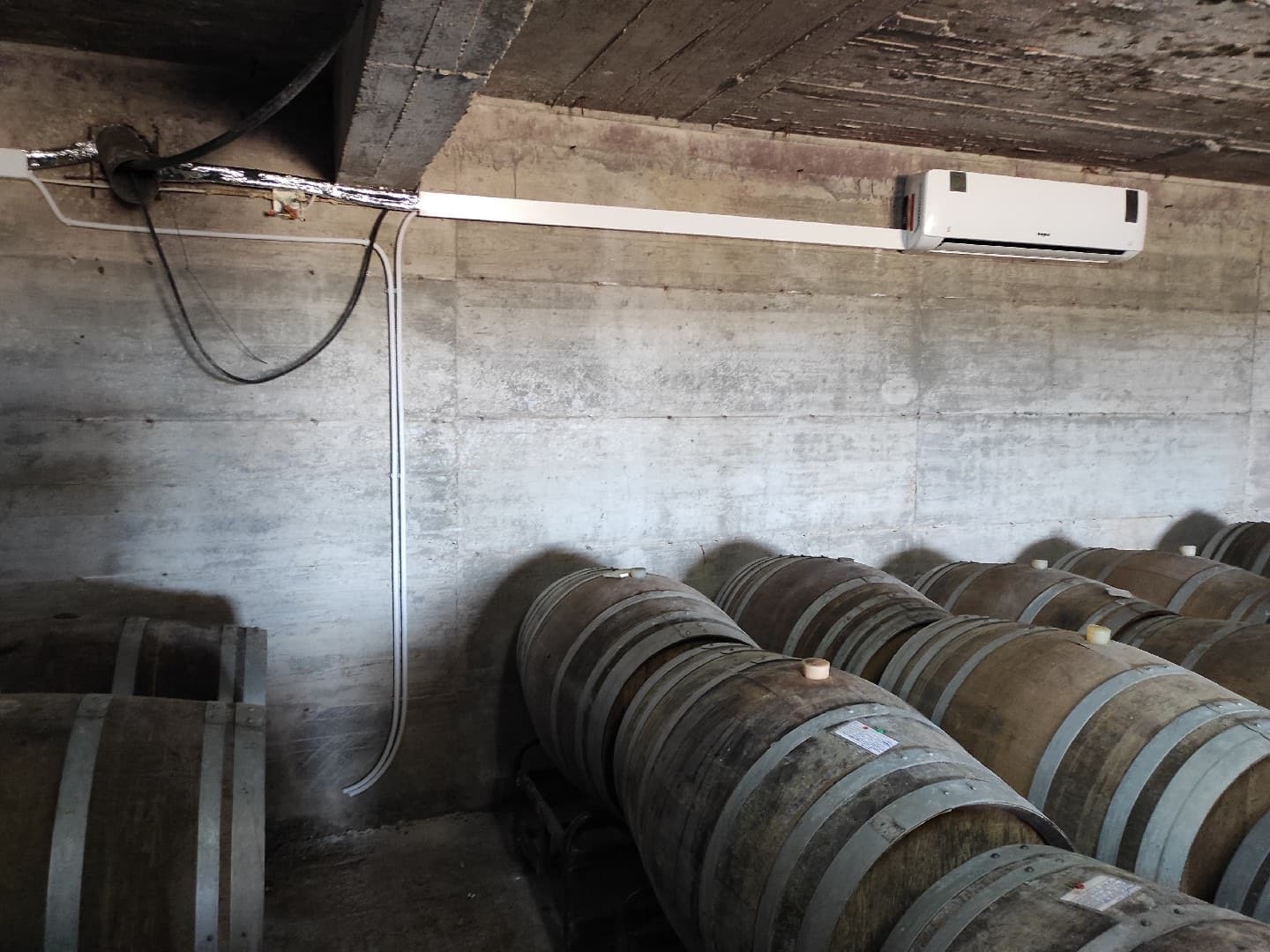 Air conditioning installed in a wine cellar, among oak barrels