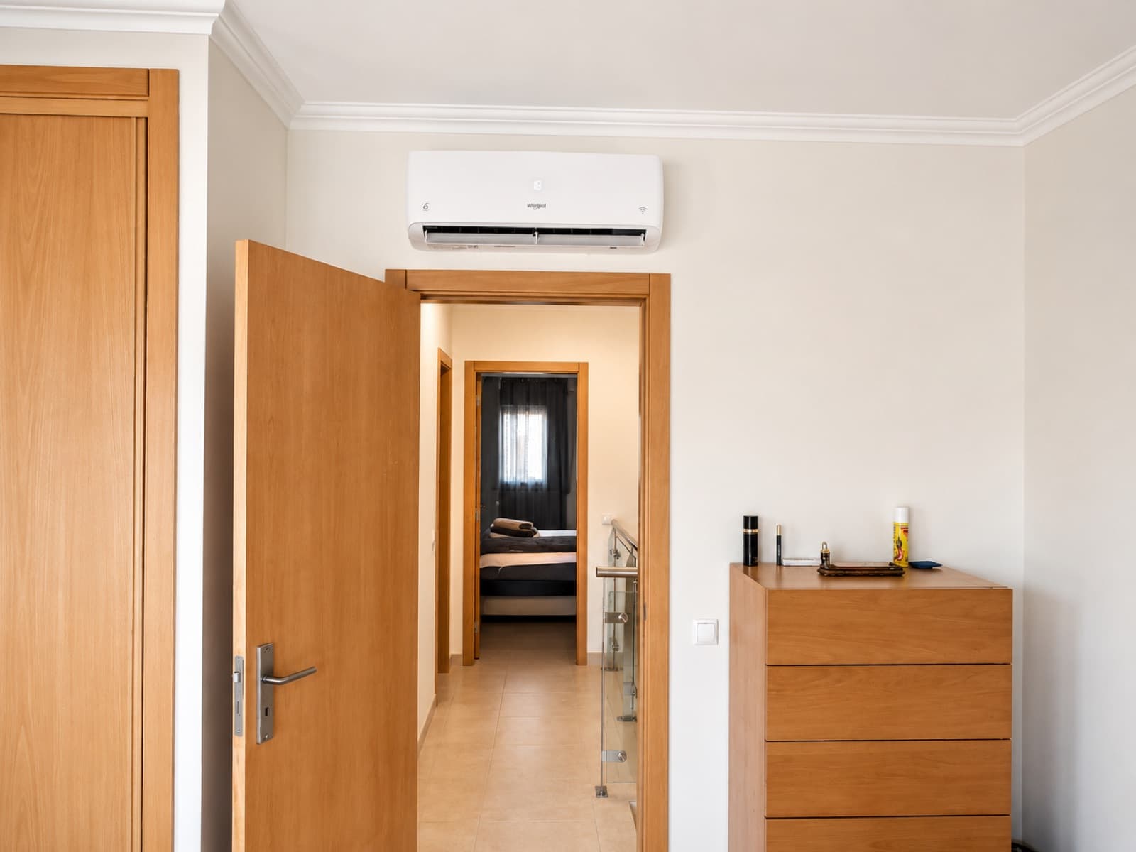 Ar condicionado Whirlpool instalado num corredor, por cima de uma porta aberta
