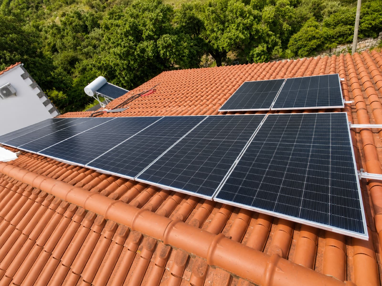 Painéis solares instalados numa cobertura de telha, junto a um painel solar térmico
